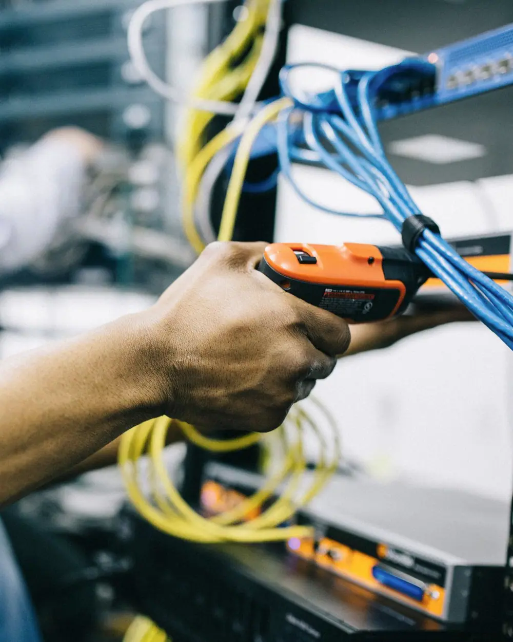 Technician testing structured cabling terminated into a rack-mounted network switch