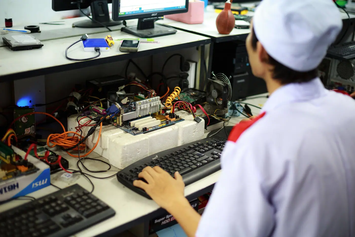 Technician servicing a computer motherboard at an IT hardware repair bench
